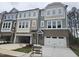 Modern townhome boasts an attached garage, complemented by large windows and brick and siding details at 5028 Jowetts Walk Dr # 24, Cary, NC 27519