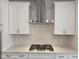 Close-up of gas range, stainless hood and white cabinets with modern hardware in sleek kitchen at 5028 Jowetts Walk Dr # 24, Cary, NC 27519