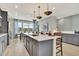 Spacious kitchen featuring gray cabinets, stainless appliances, oversized island with seating, and pendant lighting fixtures at 5028 Jowetts Walk Dr # 24, Cary, NC 27519