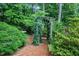 Lush landscaping features an ivy-covered archway and mature greenery for a peaceful, secluded feel at 5800 Heatherbrook Cir, Raleigh, NC 27612