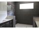 Modern bathroom featuring dark gray tiled walls, bench, and double vanity at 5900 Tranquil Cv, Youngsville, NC 27596