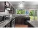 Well-lit kitchen featuring dark wood cabinetry, granite countertops, and stainless steel appliances at 612 Quartz Dr, Durham, NC 27703