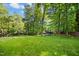 Spacious backyard with lush green grass, mature trees, and outdoor recreation equipment at 6912 Baywood Dr, Raleigh, NC 27613