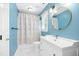 Bright bathroom featuring blue walls, a shower with a curtain, and a framed round mirror at 6912 Baywood Dr, Raleigh, NC 27613