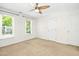 Bright bedroom featuring two windows, a ceiling fan, neutral carpet, and ample natural light at 6912 Baywood Dr, Raleigh, NC 27613