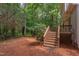 View of back deck and stairs, with a backyard featuring mature trees and pine straw ground cover at 7 Hitching Rack Ct, Durham, NC 27713