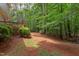 Backyard with a wooden deck, mature trees, and a pathway covered in pine straw at 7 Hitching Rack Ct, Durham, NC 27713