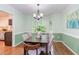 Sunlit dining room with a dark wood table, light colored chairs, and view of the kitchen at 7 Hitching Rack Ct, Durham, NC 27713
