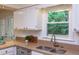 Bright kitchen boasts stainless steel sink, white cabinetry, and granite countertop at 7 Hitching Rack Ct, Durham, NC 27713