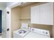 Functional laundry room with a washer, dryer, white cabinets, and a shelf for storage at 7 Hitching Rack Ct, Durham, NC 27713
