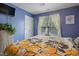 Cozy bedroom with blue walls, window, and floral patterned comforter creating an inviting atmosphere at 750 Raymond Dr, Clayton, NC 27527