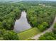 Scenic aerial view of a calm lake surrounded by lush greenery and a nearby road at 7520 Milestone Ct, Raleigh, NC 27615