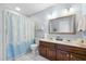 Well-lit bathroom featuring a double sink vanity and a shower with stylish curtain at 7520 Milestone Ct, Raleigh, NC 27615