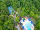 Bird's-eye view of a community pool and tennis courts, all enveloped by verdant trees at 7520 Milestone Ct, Raleigh, NC 27615