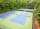 Aerial image of several well-maintained tennis courts surrounded by green trees at 7520 Milestone Ct, Raleigh, NC 27615