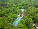 Aerial view of tennis courts and a pool nestled among mature trees at 7520 Milestone Ct, Raleigh, NC 27615