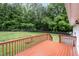 View from the wood deck to the backyard with large green trees and chain-link fencing at 7603 Nichols Dr, Rougemont, NC 27572