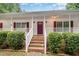 Inviting front porch with brick steps and white railings, framed by manicured bushes at 7603 Nichols Dr, Rougemont, NC 27572