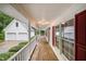 View down the expansive covered porch showcasing wood flooring and access to the detached garage at 7603 Nichols Dr, Rougemont, NC 27572