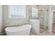 Bright bathroom with a soaking tub, walk-in shower with glass door, and large window at 7719 Barefoot Rd, Fuquay Varina, NC 27526