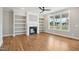 Sunlit living room with fireplace, built-in shelving, hardwood floors, and large windows at 7719 Barefoot Rd, Fuquay Varina, NC 27526