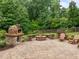 Paver patio with pizza oven, fire pit, and wood chairs in fenced-in backyard with surrounding greenery at 109 Henrys Ridge Rd, Pittsboro, NC 27312