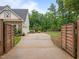 Gated driveway leading to a large three-car garage and a lushly landscaped yard with privacy fence at 109 Henrys Ridge Rd, Pittsboro, NC 27312