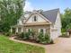 Exterior view of a home featuring a stone and white shingle exterior, three car garage, mature trees at 109 Henrys Ridge Rd, Pittsboro, NC 27312