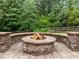 Stone fire pit on paver patio surrounded by a curved stone bench, fenced in backyard with trees and greenery at 109 Henrys Ridge Rd, Pittsboro, NC 27312