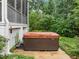 Hot tub sitting on a concrete pad next to the house, with greenery in the fenced-in backyard at 109 Henrys Ridge Rd, Pittsboro, NC 27312