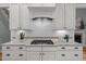 Close-up of kitchen stove with white cabinets, subway tile backsplash, granite counters, and stainless hood at 109 Henrys Ridge Rd, Pittsboro, NC 27312