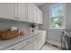Bright laundry room features custom cabinetry, stainless steel appliances and a sink beneath a window at 109 Henrys Ridge Rd, Pittsboro, NC 27312
