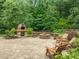 Outdoor patio area with a stone pizza oven, fire pit with seating, and mature trees at 109 Henrys Ridge Rd, Pittsboro, NC 27312