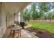Covered patio with seating area overlooks landscaped yard with mature trees at 109 Henrys Ridge Rd, Pittsboro, NC 27312