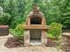 Stone pizza oven with brick interior and stone base, surrounded by lush landscaping in backyard at 109 Henrys Ridge Rd, Pittsboro, NC 27312