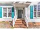 Close-up of blue sided home's front entrance, showcasing brick steps and blue shutters at 11113 N Radner Way, Raleigh, NC 27613