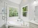 Bright bathroom with large soaking tub below window and a separate glass-door shower at 113 Bergeron Way, Cary, NC 27519