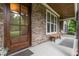 Inviting covered porch with stone detail, a wooden bench and a solid wood door adding warmth at 114 Margaret Mann Way, Pittsboro, NC 27312