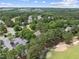 An aerial view captures homes nestled among trees near a golf course and a parking lot in the distance at 1300 Heritage Club Ave, Wake Forest, NC 27587