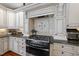 Modern kitchen features custom white cabinetry, stainless steel appliances, granite countertops and tiled backsplash at 1300 Heritage Club Ave, Wake Forest, NC 27587