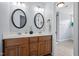 Bathroom featuring a dual sink vanity with a white countertop, wooden cabinets, and oval mirrors at 1633 Lakestone Village Ln, Fuquay Varina, NC 27526