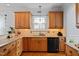 Bright kitchen featuring granite countertops, wood cabinets, stainless steel appliances, and a black dishwasher at 1633 Lakestone Village Ln, Fuquay Varina, NC 27526