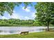 Scenic pond view with mature trees and a park bench, perfect for relaxation at 1633 Lakestone Village Ln, Fuquay Varina, NC 27526