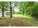 Spacious backyard with mature trees and an outbuilding, perfect for outdoor entertaining at 1822 Routh Rd, Burlington, NC 27217