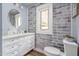 Well-lit bathroom with a white vanity, mirror, and gray brick accent wall at 1822 Routh Rd, Burlington, NC 27217