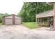 Exterior shot of detached two-car garage and covered patio with brick base on lush green lot at 1822 Routh Rd, Burlington, NC 27217