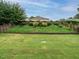 Large, grassy backyard with a fence, and a stone retaining wall with bushes and trees at 1833 Creek Oak Circle Cir, Fuquay Varina, NC 27526