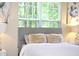 Close-up of bright bedroom showing cozy pillows, a comfortable bed, headboard, and light from a large window at 1912 Parkside Village Dr, Clayton, NC 27520