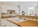 The kitchen has white cabinetry and tiled backsplash with an open view to the living area at 1912 Parkside Village Dr, Clayton, NC 27520