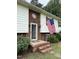 Close up on the charming front entrance, showcasing brickwork and an American flag display at 210 Crest Rd, Henderson, NC 27536